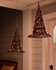 Set of lit decorative wire witch's hats displayed on a porch