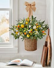 Orange and yellow blooms in a hanging basket, a cookbook, and wooden chopping boards in corner