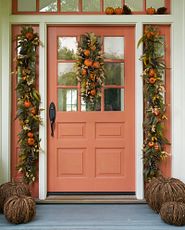 Front door decorated with autumn swag, garlands, and pumpkins
